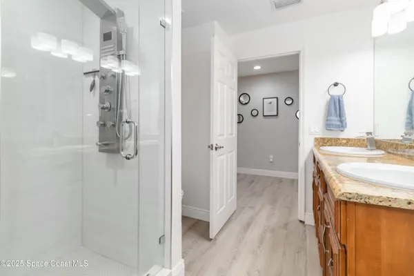 a bathroom with a granite countertop sink a mirror and shower