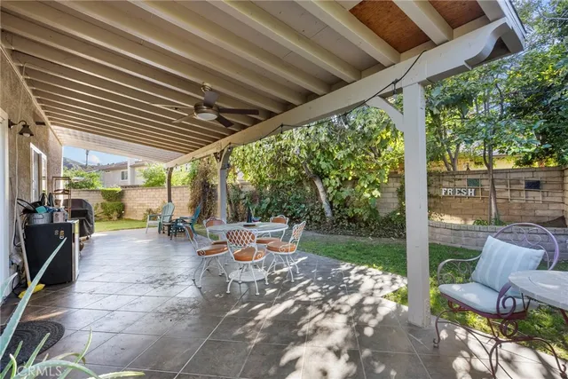 a view of a patio with table and chairs potted plants and floor to ceiling window