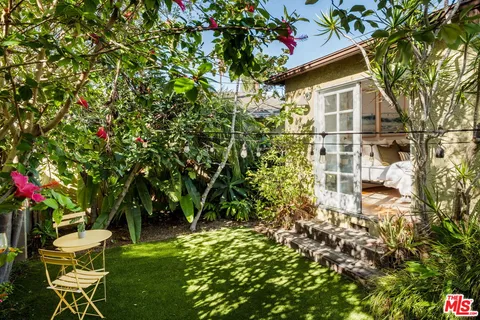a backyard of a house with table and chairs and potted plants