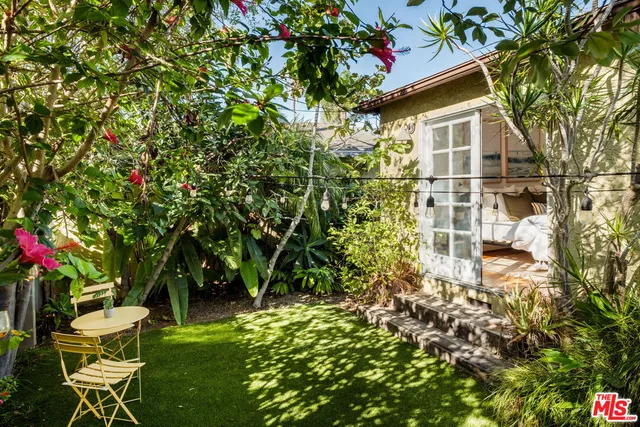a backyard of a house with table and chairs and potted plants
