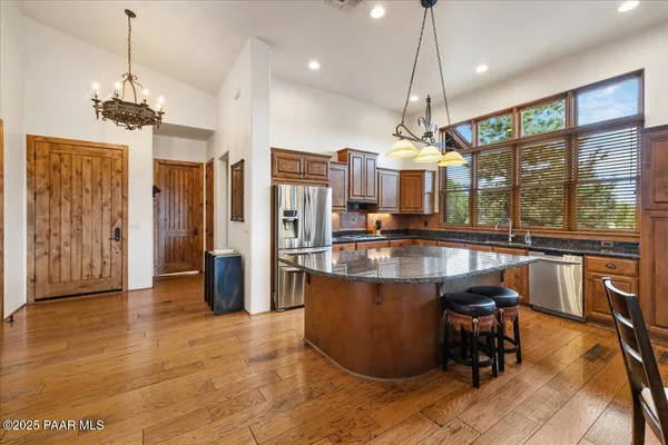 a kitchen with stainless steel appliances granite countertop a dining table chairs and wooden floor