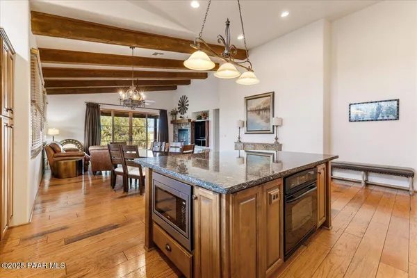 a dining room with wooden floor a chandelier a glass table and chairs