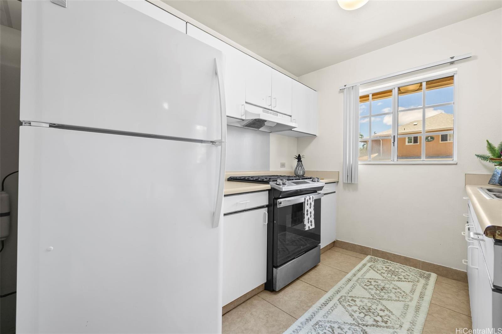 91-1008 Makaaloa Street, Unit 3E Ewa Beach, HI 96706 - Photo 7 of 21 a kitchen with stainless steel appliances granite countertop a refrigerator and a stove top oven