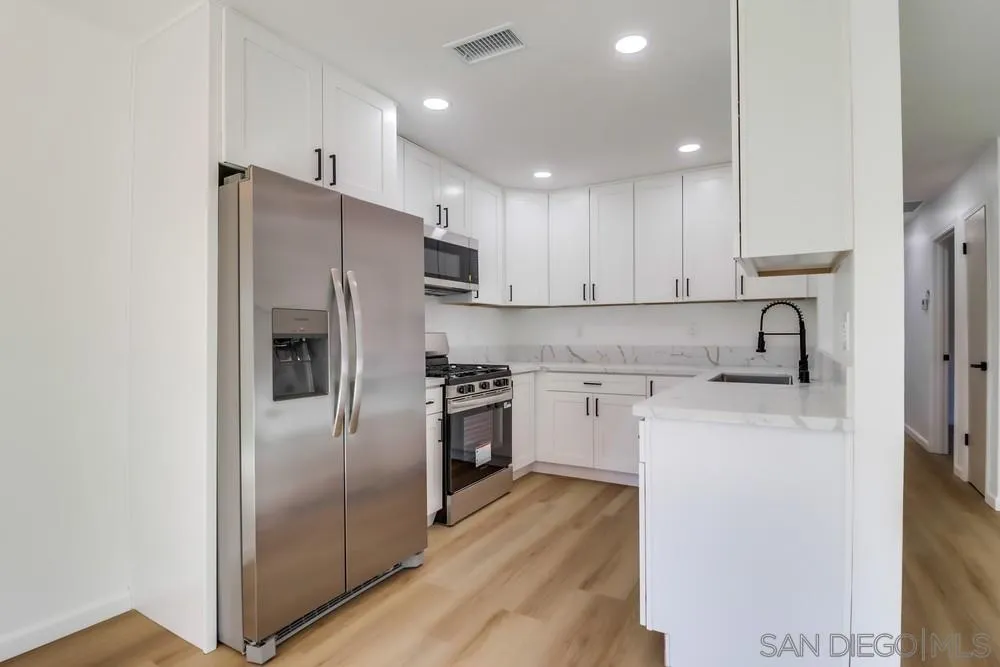 2821-25 Rosedale Way Spring Valley, CA 91977 - Photo 32 of 72 a kitchen with stainless steel appliances granite countertop a refrigerator a stove and a sink with wooden floor