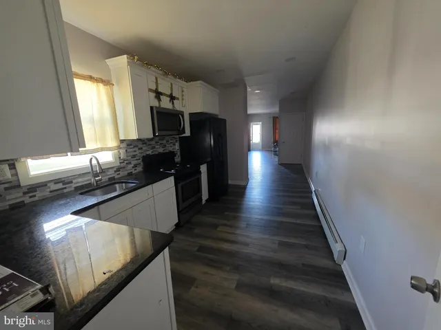 a kitchen with sink a refrigerator and white cabinets