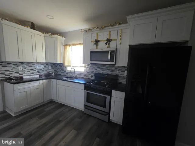 a kitchen with granite countertop a refrigerator stove a sink and dishwasher with wooden floor