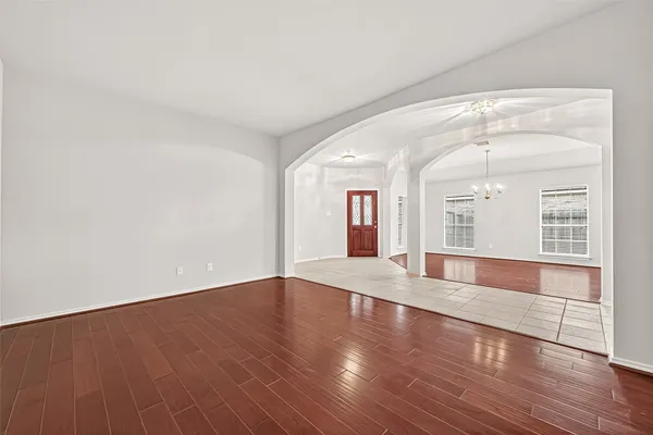 an empty room with wooden floor fireplace and windows