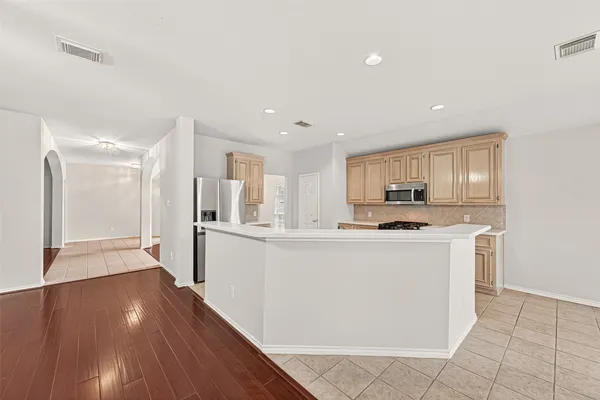 a kitchen with stainless steel appliances granite countertop a refrigerator a sink a stove and white cabinets with wooden floor