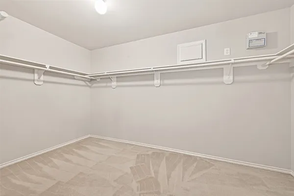 a view of an empty room with chandelier fan and fire place