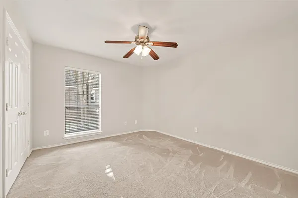 an empty room with a window and a fan