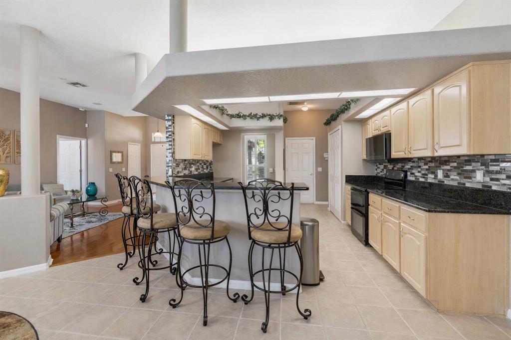 1602 Kish Boulevard Trinity, FL 34655 - Photo 23 of 65 a kitchen with stainless steel appliances kitchen island granite countertop a stove a sink a dining table and chairs