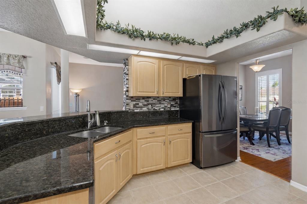 1602 Kish Boulevard Trinity, FL 34655 - Photo 25 of 65 a kitchen with kitchen island granite countertop a refrigerator a sink and white cabinets