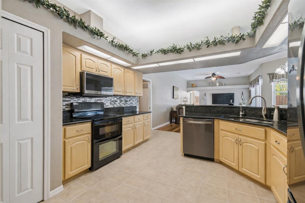 1602 Kish Boulevard Trinity, FL 34655 - Photo 26 of 65 a kitchen with stainless steel appliances granite countertop a stove top oven a sink dishwasher and a microwave oven with white cabinets