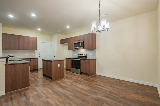 a kitchen with stainless steel appliances granite countertop a sink cabinets and wooden floor