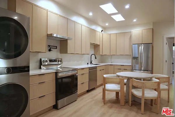 a kitchen with a sink white cabinets and stainless steel appliances