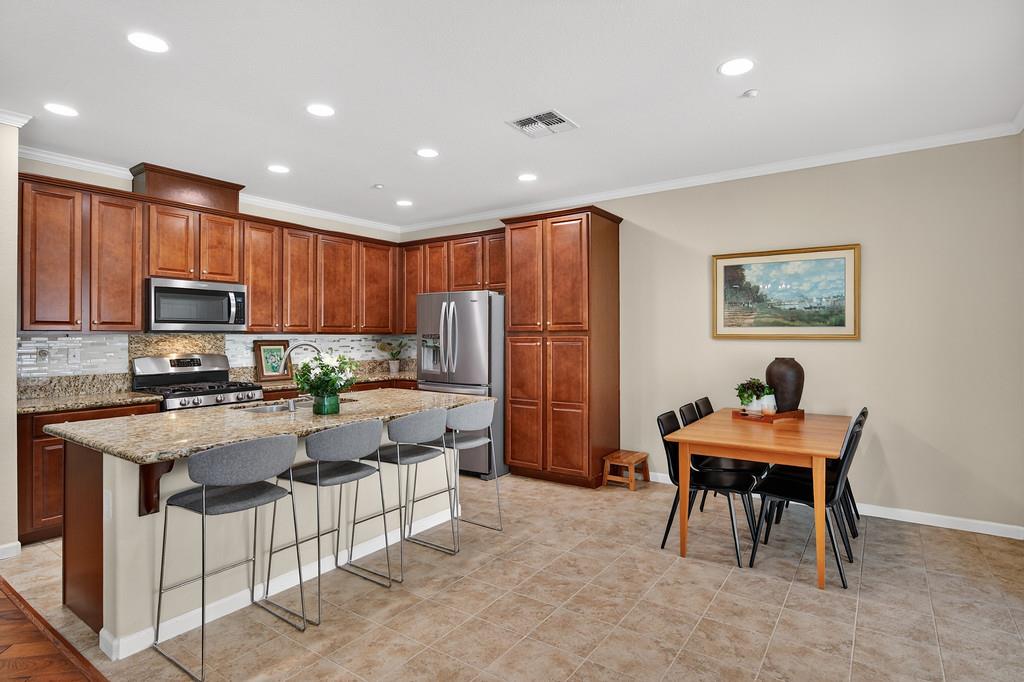 5409 Mill Water Circle Rancho Cordova, CA 95742 - Photo 17 of 48 a kitchen with stainless steel appliances kitchen island granite countertop a refrigerator a stove a sink a dining table and chairs with wooden floor