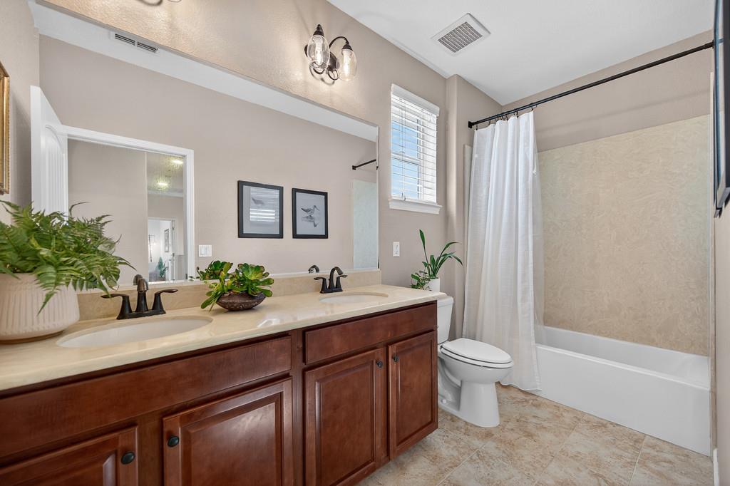 5409 Mill Water Circle Rancho Cordova, CA 95742 - Photo 25 of 48 a bathroom with a granite countertop sink a toilet a large mirror and shower