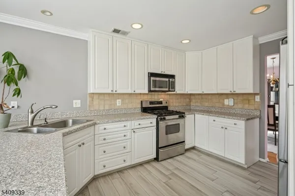 a kitchen with white cabinets sink and stainless steel appliances