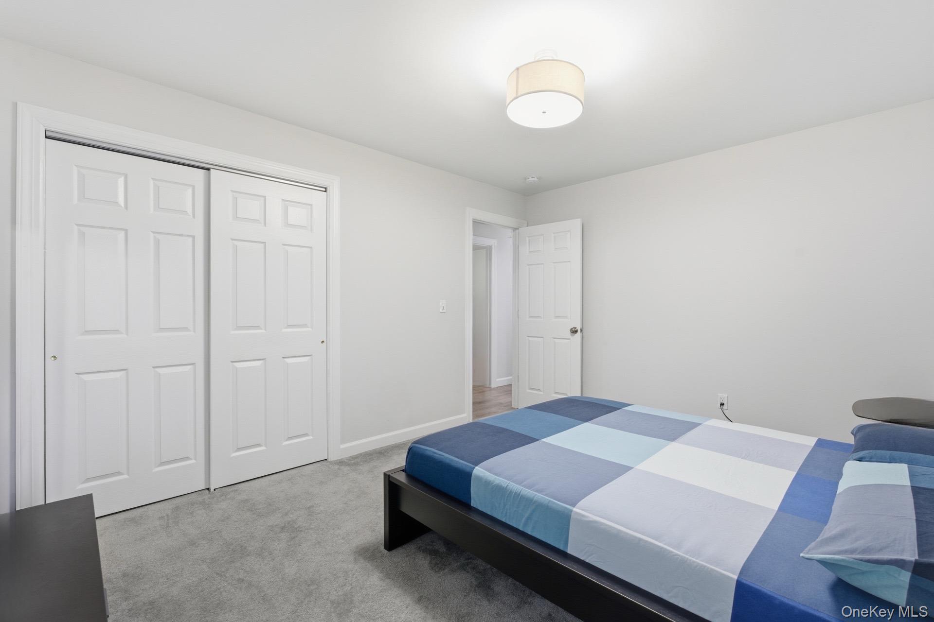 130 Beaver Dam Road Brookhaven, NY 11719 - Photo 9 of 15 a bedroom with a bed and a chandelier