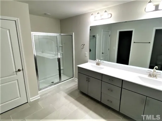 a bathroom with a double vanity sink mirror and shower