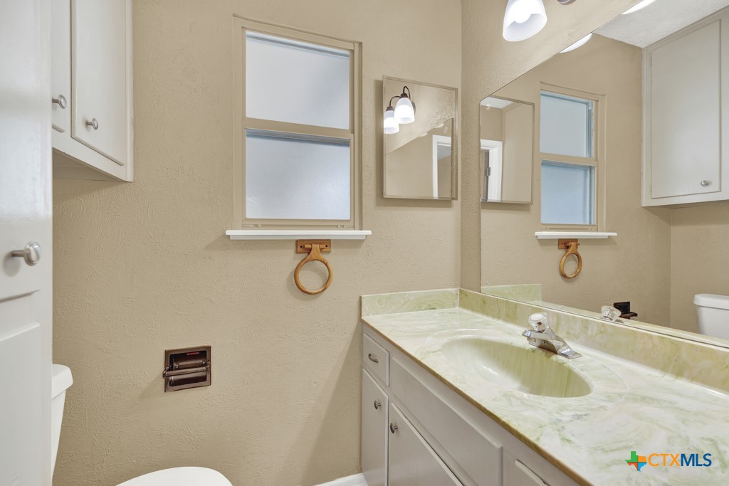 217 Gruene Road New Braunfels, TX 78130 - Photo 13 of 25 a bathroom with a granite countertop sink a mirror and a toilet