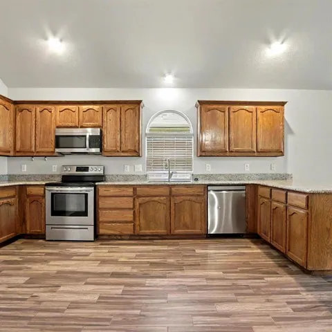 a kitchen with stainless steel appliances granite countertop a stove a sink and a microwave