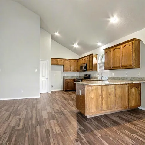 a kitchen with granite countertop a stove top oven and cabinets