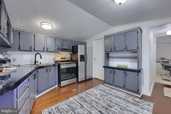 a kitchen with stainless steel appliances granite countertop a refrigerator stove top oven and sink