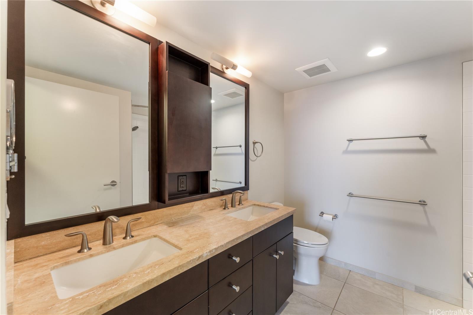 1189 Waimanu Street, Unit 2204 Honolulu, HI 96814 - Photo 7 of 17 a bathroom with a granite countertop sink toilet and mirror