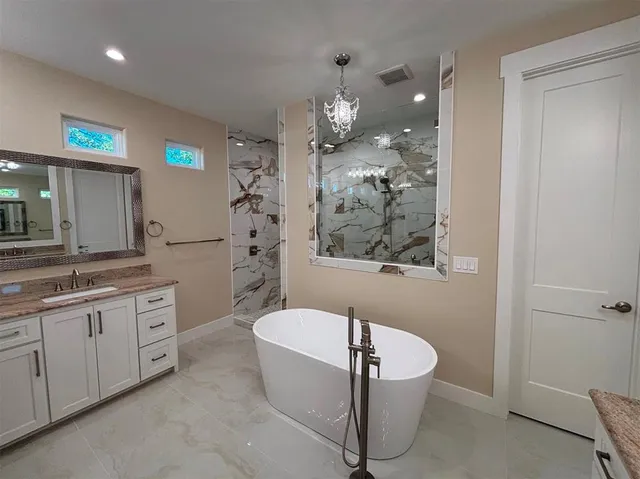 a bathroom with a granite countertop sink mirror bathtub and toilet