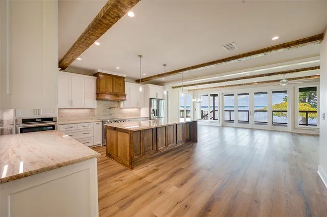 a kitchen with stainless steel appliances granite countertop a lot of cabinets and wooden floor