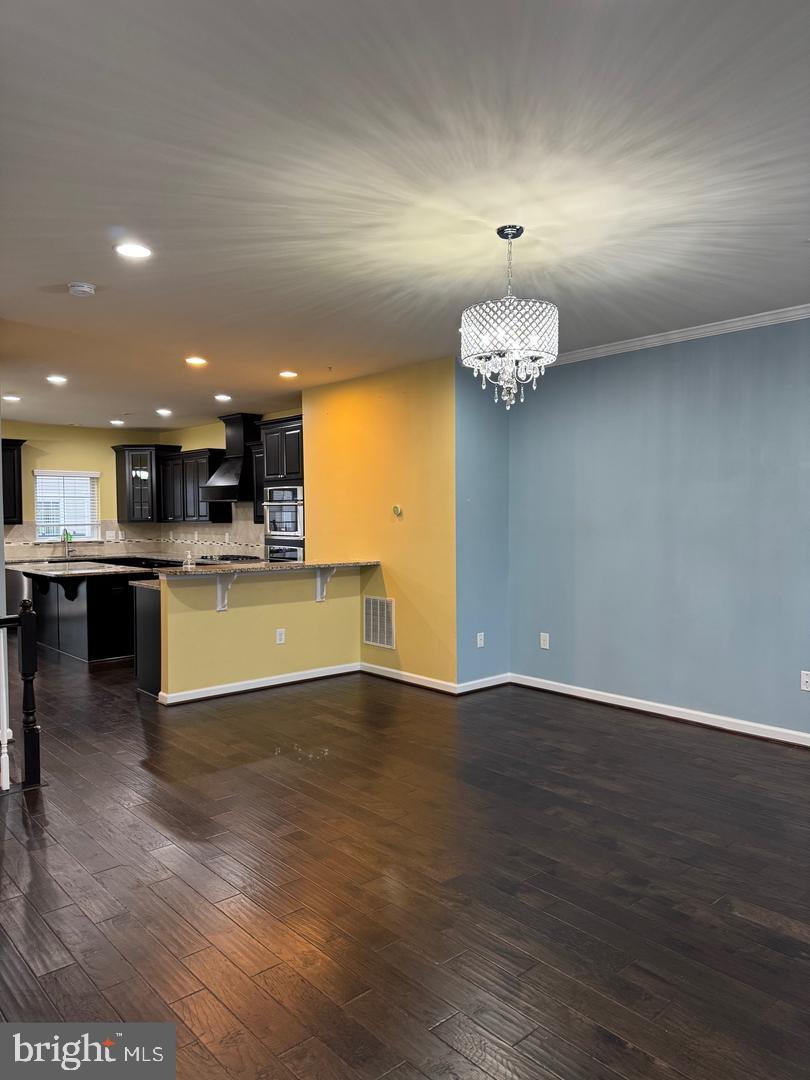 7925 Alchemy Way Elkridge, MD 21075 - Photo 16 of 46 a view of a kitchen with a chandelier wooden floor and a fireplace