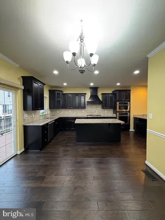 a large kitchen with stainless steel appliances granite countertop a stove a sink dishwasher a microwave oven and a granite countertops with wooden floor