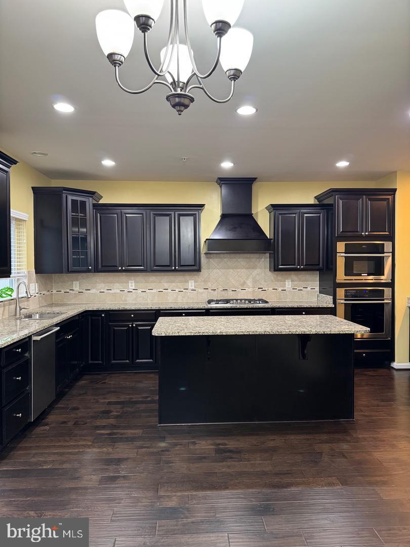 7925 Alchemy Way Elkridge, MD 21075 - Photo 25 of 46 a large kitchen with stainless steel appliances granite countertop a stove a sink dishwasher a microwave oven and a granite countertops with wooden floor