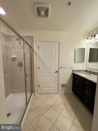 a spacious bathroom with a granite countertop sink a mirror and a shower