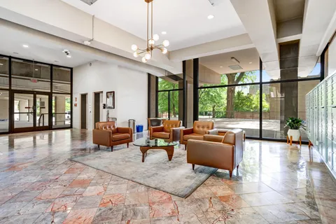 a living room with furniture large windows and wooden floor