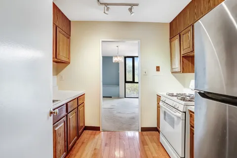 a kitchen with a refrigerator a stove top oven and a wooden floor