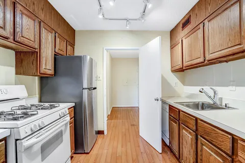 a kitchen with stainless steel appliances granite countertop a sink stove refrigerator and cabinets
