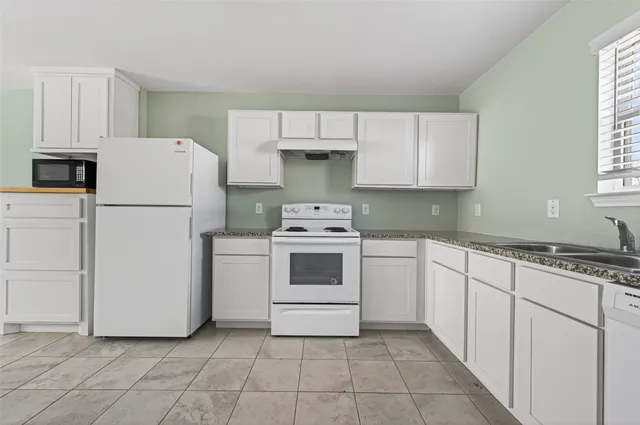a kitchen with a stove a refrigerator and white cabinets