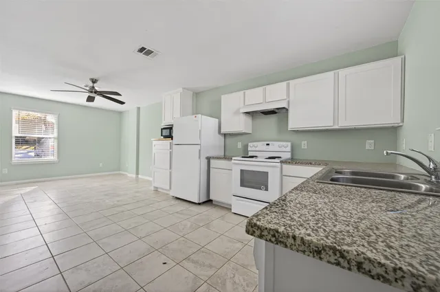 a kitchen with cabinets stove and white stainless steel appliances