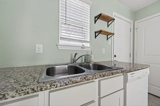 a view of an empty room with window and chandelier fan