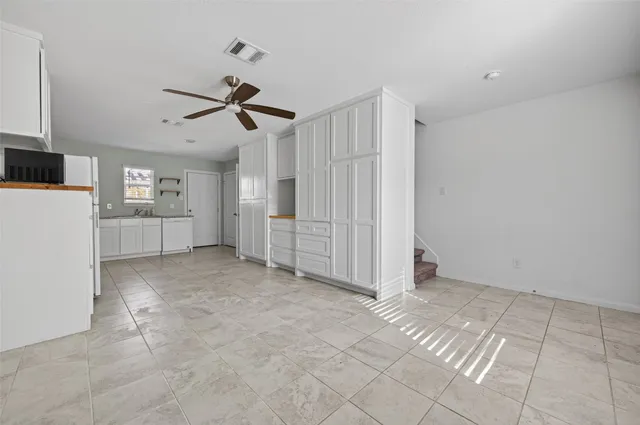 a view of an empty room with a ceiling fan and window