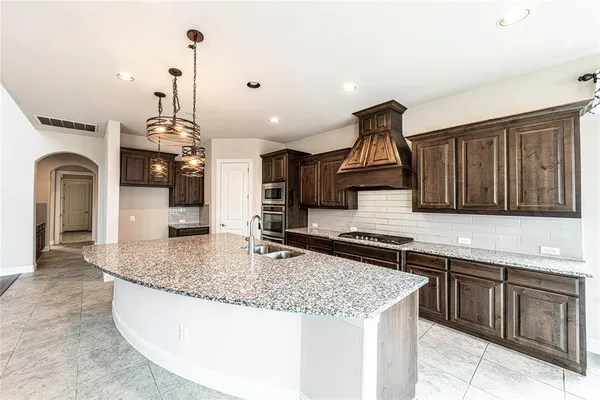 a large kitchen with stainless steel appliances kitchen island granite countertop a large counter top a stove and a sink