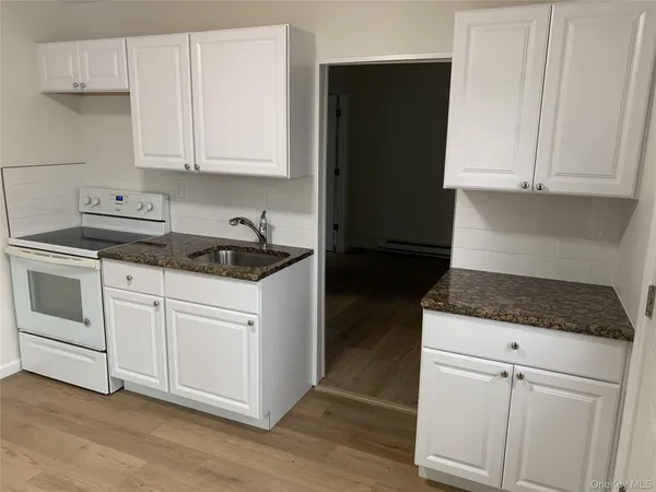 a kitchen with white cabinets and appliances