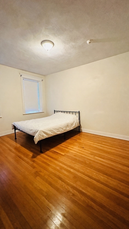 57 Alton Place, Unit 3 Brookline, MA 02446 - Photo 12 of 13 a living room with hard wood floors and a bed