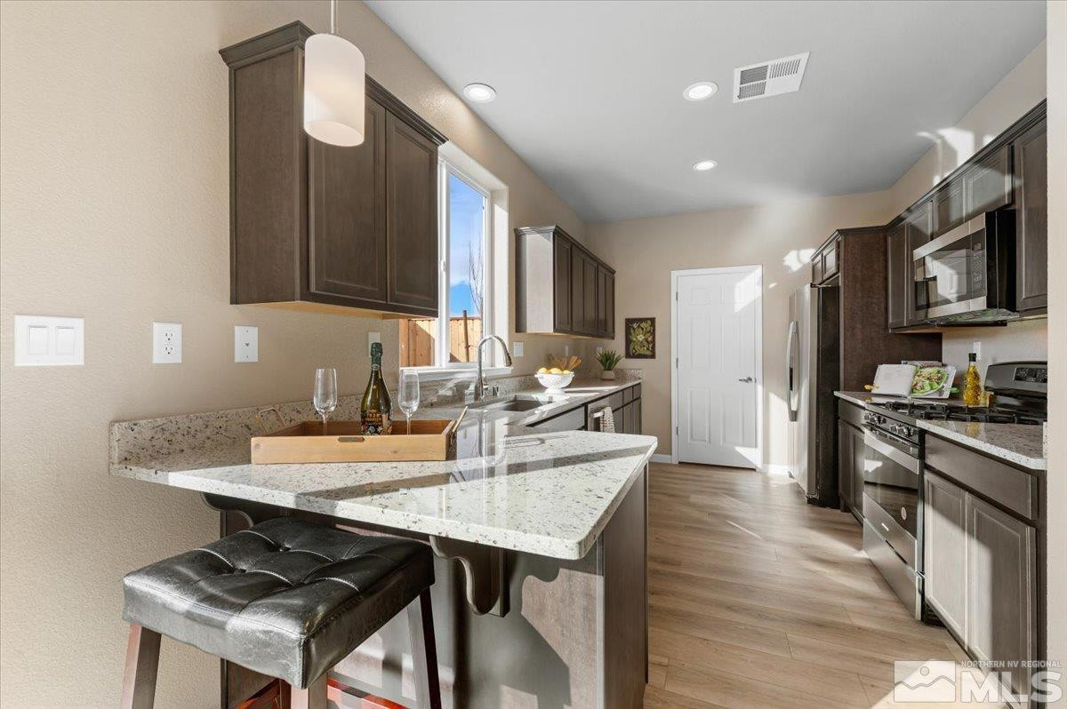 1180 Arrastra Road, Unit LOT 15 Reno, NV 89512 - Photo 10 of 34 a kitchen with stainless steel appliances granite countertop a stove refrigerator a sink dishwasher a dining table and chairs with wooden floor