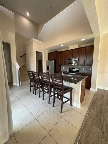 a kitchen with stainless steel appliances a microwave a stove a sink a dining table and chairs