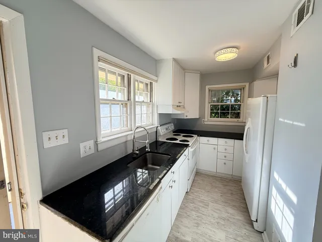 a kitchen with granite countertop a stove a sink and a refrigerator