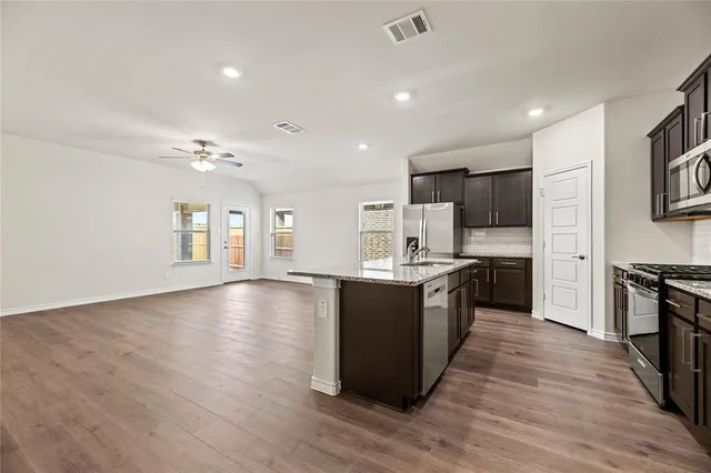 a kitchen with stainless steel appliances granite countertop a sink a stove a refrigerator and cabinets