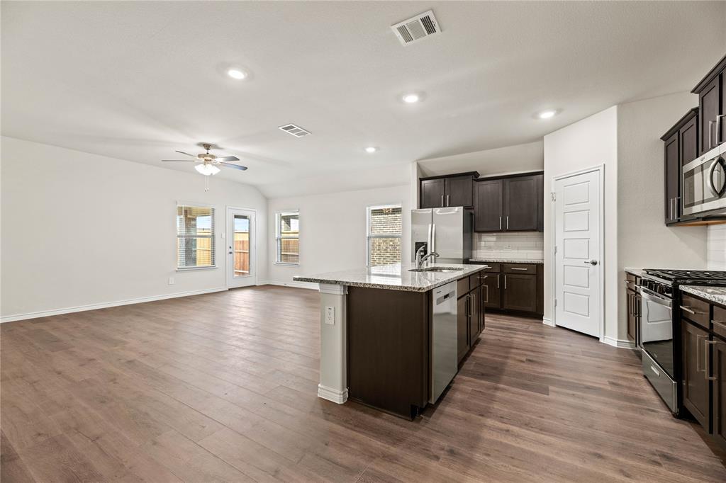 411 Revolution Road Fate, TX 75087 - Photo 14 of 34 a large kitchen with stainless steel appliances granite countertop a large center island and a sink